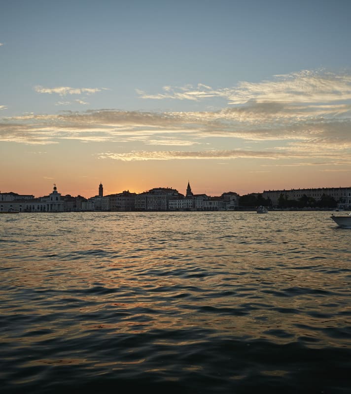 Sunset view from the Canale di San Marco towards Venice, with its silhouettes of church spires and basilica domes.
