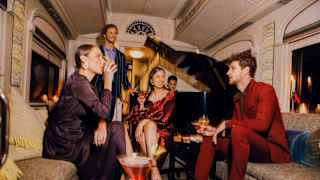 Guests drinking cocktails and smiling happily at the Piano Bar Car
