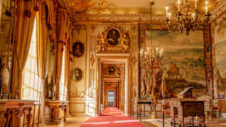 Sun pouring through windows of Blenheim Palace's State Rooms illuminates the gilded frames, chandeliers and ornate cornices.