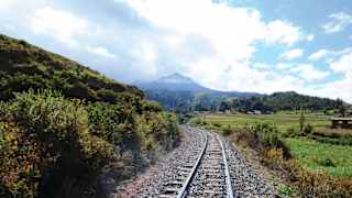 Train tracks winding along a valley towards a Peruvian mountain top