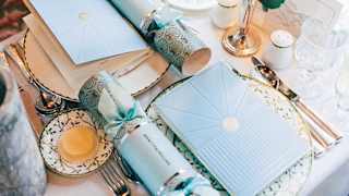 A festive table is set for two with pale blue menus and Christmas crackers set on Sultan's Garden crockery in the Zena carriage.