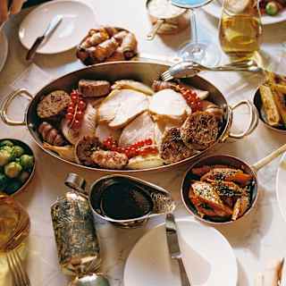 A festive feast of roast turkey with carrots, parsnips, sprouts and gravy, enjoyed with Christmas crackers, seen from above.