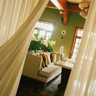 Angled view through translucent drapes into Y restaurant, where a long sofa lined with cushions faces dining tables.