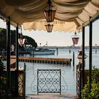 Looking from beneath the canopied entrance of Hotel Cipriani to a wrought iron fence at the canal's edge.