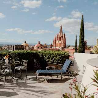 A table-set and a lounger enjoy stunning terrace views from Casa Limon over the city and Parroquia de San Miguel Arcangel.