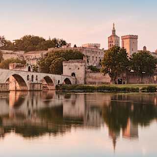 The medieval arches of Pont Saint-Bénézet bathed in a rose light at dusk