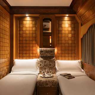 A tray rests on an upright banquette seat between two fold-down single beds with crisp linen, cosy in the low-lit wood cabin.