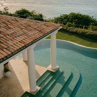 Aerial view of the terracotta-roofed veranda with column supports extending into the pool, with access steps on both sides.