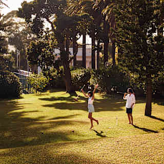 Cheerful woman jumping and smiling while playing croquet