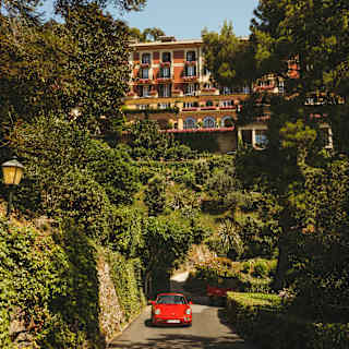 A red Ferrari drives up the road away from the terracotta hotel, which sits like a palace above terraced gardens.