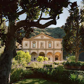 The Michelangelo-designed facade stands with palest pink walls amid a sea of green as lush hills climb up behind the gardens