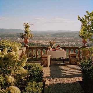 A lunch table on a rustic terrace overlooking Florence bakes in heat and romance, taken by Photographer François Halard.