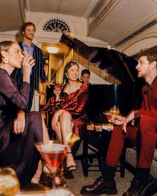 Guests drinking cocktails and smiling happily at the Piano Bar Car