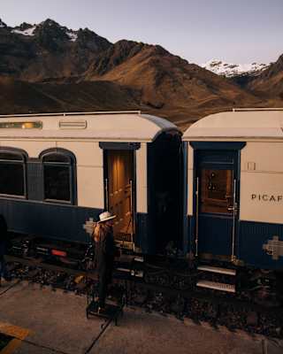 A woman in a fedora hat stepping in the carriage of the Andean Explorer