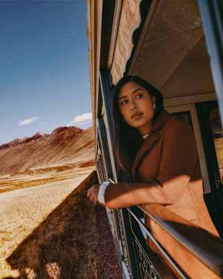 A woman in a brown blazer standing on the train's open-air observation deck