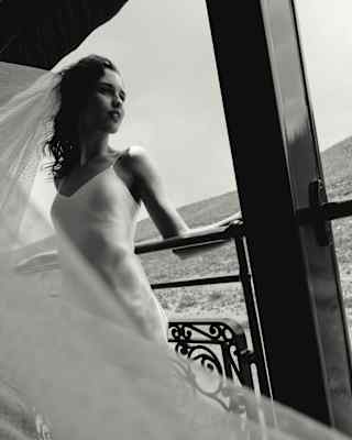 A lace veil floats across frame in a low-angle monochrome image of a bride as she leans back on the observation deck rails.