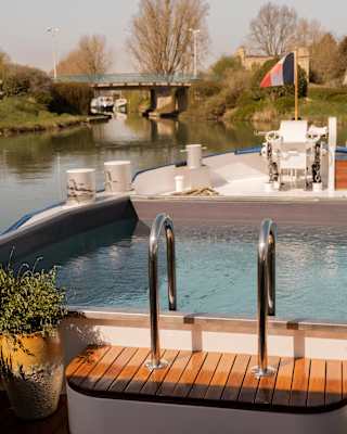 View over the plunge pool at the prow of the Lilas as it noses its way towards a bridge spanning a serene Burgundy canal.