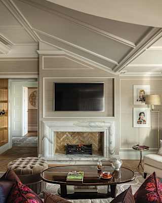 A marble fireplace draws your attention in an elegantly furnished sitting room with a garret-shaped angular ceiling