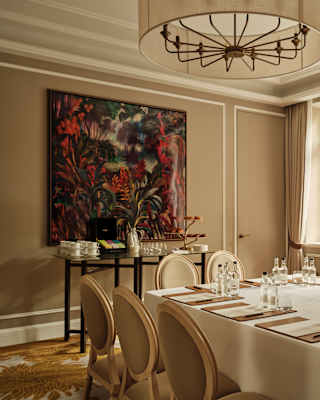 A table with paper, pens and water awaits eight guests in the Oscar venue, which has soft taupe décor and a red-tone artwork.