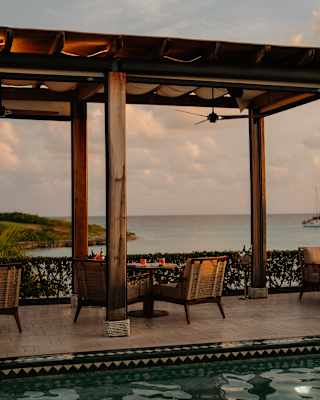View across the pool feature on Uchu's terrace to a table for four beneath a canopied pergola with glorious ocean views.