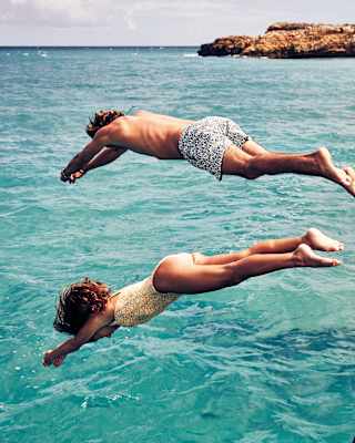 A couple diving into clear turquoise water from a boat