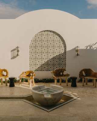 The spa's arrival courtyard offers seating in a peaceful space with a stone water feature and intricate mosaic wall panel.