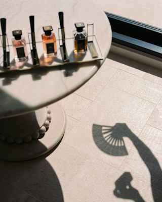 The shadow of someone holding a fan falls on the tiled floor of the spa next to a marble table with Guerlain tester bottles.