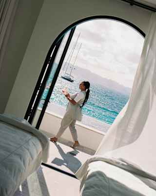 A staff member strides along a walkway overlooking sublime sea blues, viewed through the open doors of a twin treatment room.