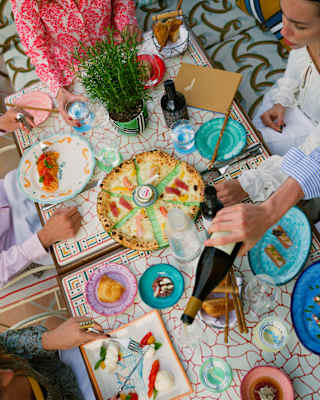 Looking down on a table of vibrant Italian dishes as a group enjoy a La Piscina lunch with wine and water.