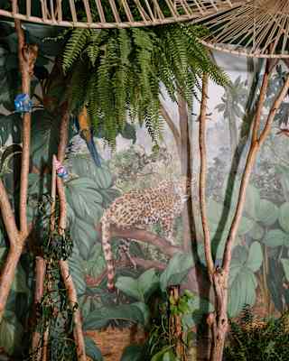 Wicker shades, hanging ferns and potted trees melt into a mural of a leopard in jungle undergrowth, in a Kids Club detail.