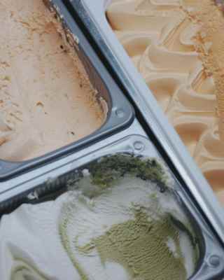 Close-up of a gelati display with a red berry sorbet, and compartments of rippled biscuit, lemon and mango-hued ice-creams.