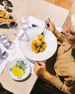 Looking down on a table where a guest enjoys a plate of pasta with red wine, bread and a lemony side dip, at Emporio Terrace.