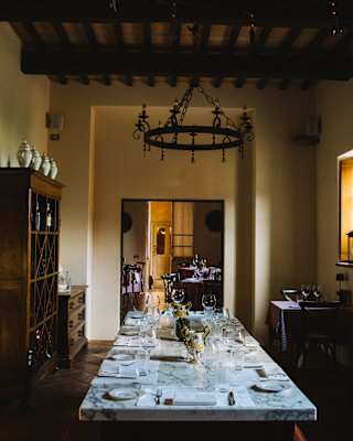 View down a long white marble table laid with cutlery, plates and glasses in a dining room with rustic wood pieces.