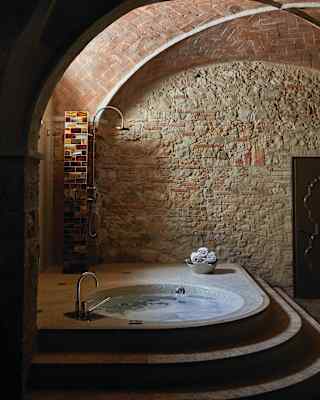Circular hot tub in a rustic, underground, stone-walled spa