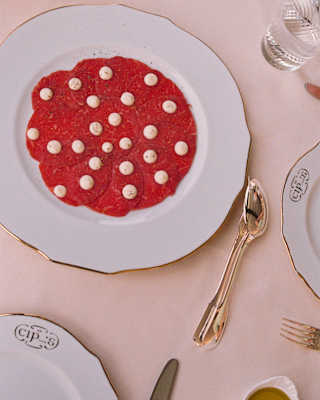 Looking down on stunning plate of Carpaccio dotted with Cipriani's traditional signature sauce, served at Cip's Club.