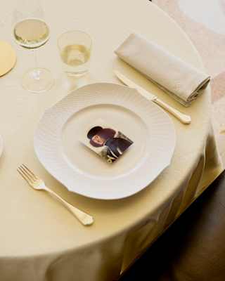 A card with a self-portrait by the Italian painter Vittore Carpaccio rests in the centre of a plate, with cutlery either side.