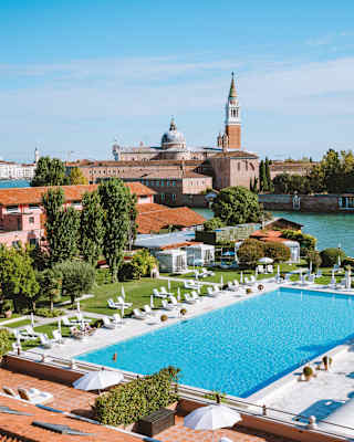 Aerial view of clay tile roofs and an outdoor pool surrounded by sunbeds and parasols