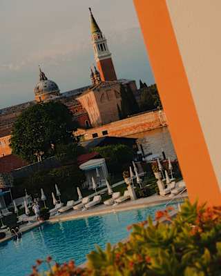 Peering out through a balcony wall is a view of the Olympic sized outdoor pool, the canal and Abbey of San Giorgio Maggiore