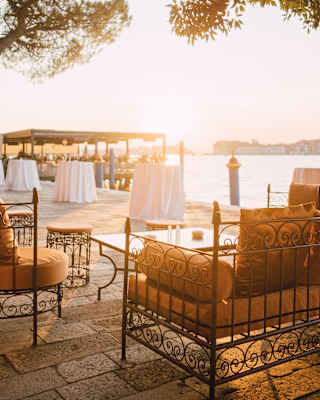 A sofa and two chairs, with filigree frames and russet cushions, enjoy canal views on the sunny waterfront behind Cip's Club.