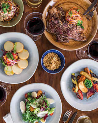 Looking down on a Pergula lunch with a selection of fresh, vibrant meat, salad and vegetable dishes, served with red wine.