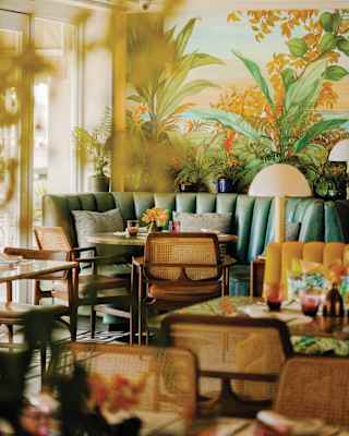 Curving green leather booths, orange table flowers, floral cushions and vibrant wallpaper give this restaurant a tropical vibe
