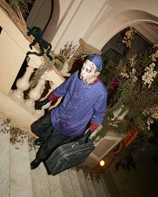 A man dressed as a ghostly bell-boy climbs the stairs inside Copacabana Palace at a Halloween party, seen from a high angle.