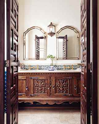 Two bathroom mirrors side-by-side above a carved wooden vanity cabinet