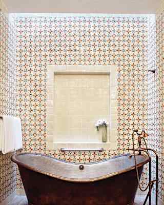 Close-up of a copper standalone bathtub surrounded by red and blue tiles