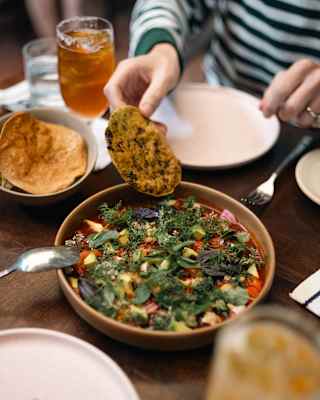 A guest dips a tortilla into a bowl of bright red shrimp Aguachile, with avocado, herbs and onion, during a lunch at Andanza.