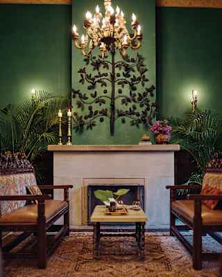 Green room with tan leather sofas either side of a large stone fireplace