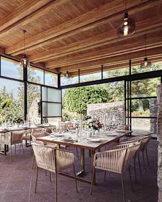 Two celebration tables await guests in a venue that brings the outside in through full length glass doors on three sides.