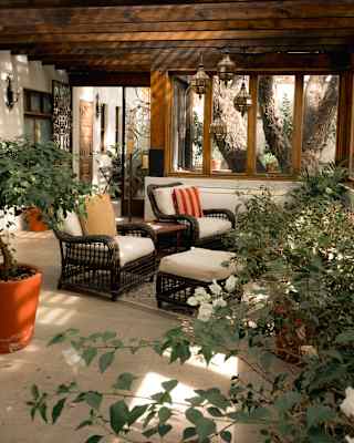 View through foliage of two lounge chairs, with white cushions and footstools, resting beneath the wood beam Spa ceiling.