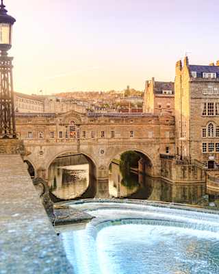View across a river of Bath city with a stone bridge and a row of Georgian houses