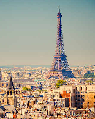 The Eiffel Tower rising above Paris skyline into clear blue skies